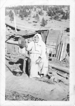 Grandmother Semenoff (Anna Nikolaeva Sophonoff b. 1858 d. 1944. married to Nikolai Fedorovich Semenoff b. 1858 d. 1918) to Mabel, John, Nick, Pete, Sam, and Harry J. Chernoff. She was born in Russia, Caucasus area, now Azerbaijan. Photo taken in Popoff Davidoff Podmeroff village above Fuitova School, Grandforks. She is sifting grain in the wind with the pan. This picture was taken in the fall. Great Grandmother Semenoff
